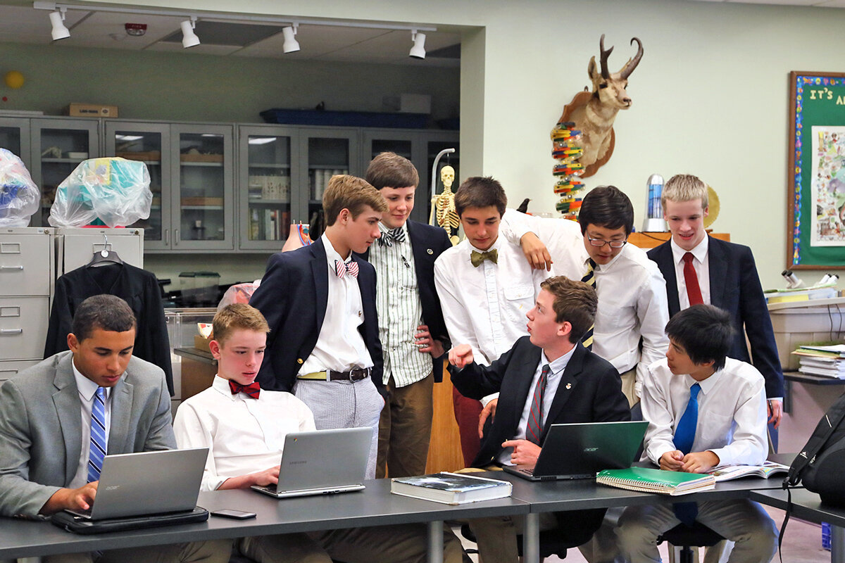 Students working at laptops in a classroom, heads bent over screens
