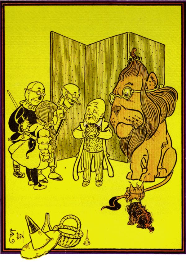 Dorothy, the Tin Man, the Scarecrow, the Lion, and Toto confront a small bald man standing in front of a folding screen. The wizard has been revealed.