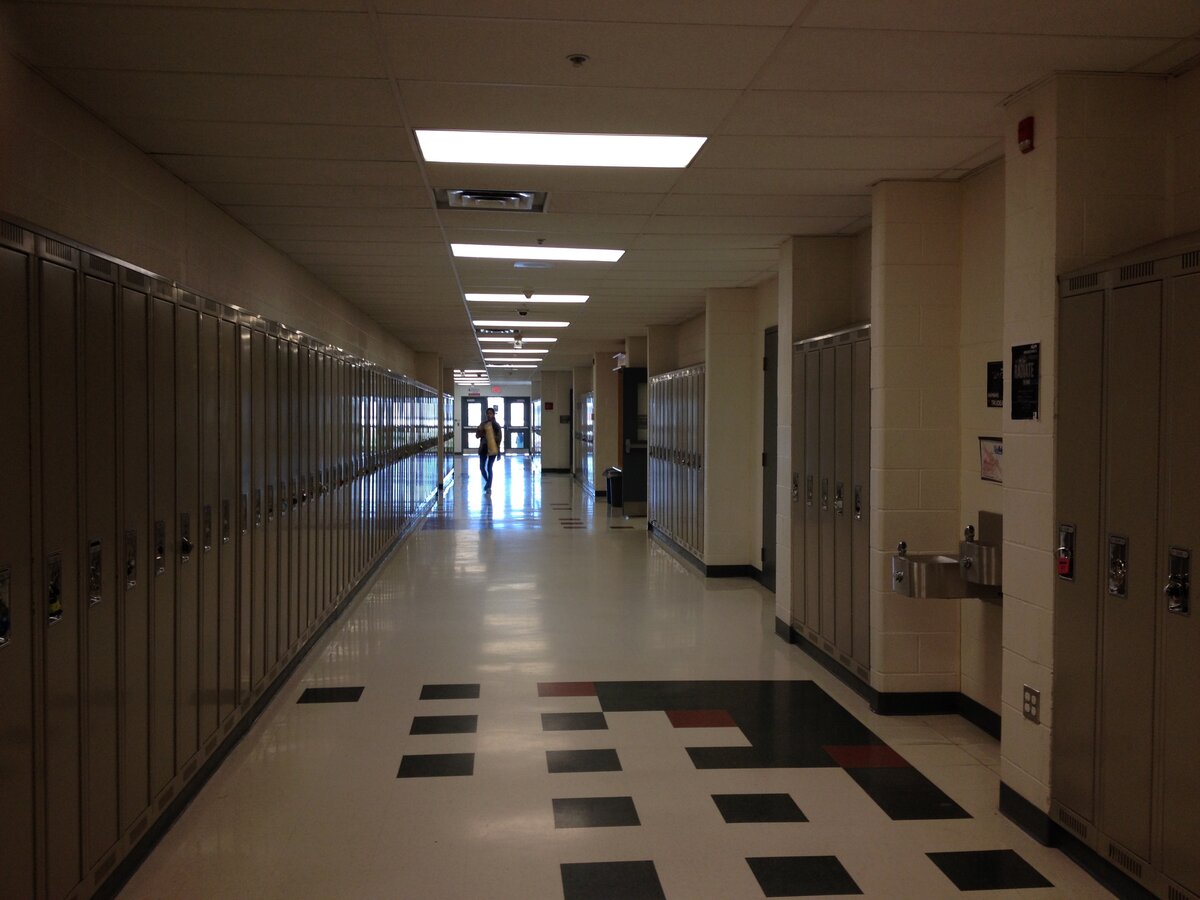 A school hallway with lockers and fluorescent lights