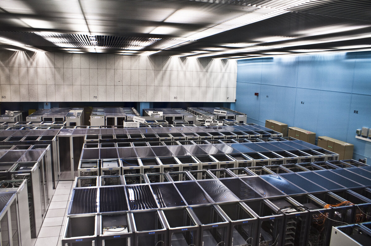 Rows of servers in a data center, blinking lights in a dim room